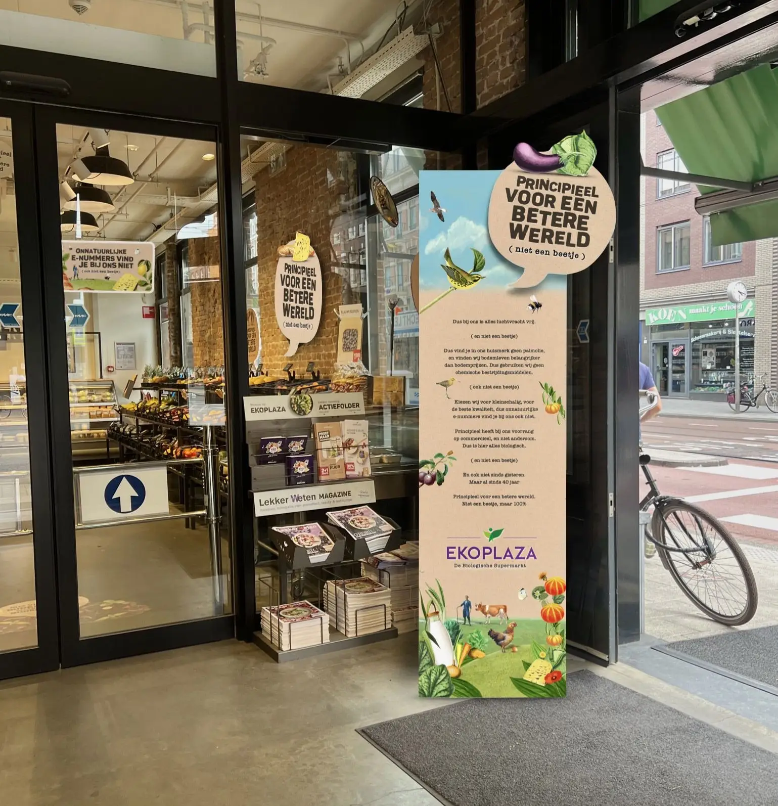 Ingang van een Ekoplaza-winkel met campagnebanier